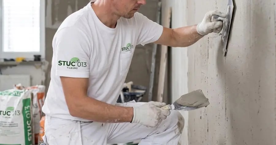 Stukadoor smeert glad pleisterwerk op muur in Tilburg