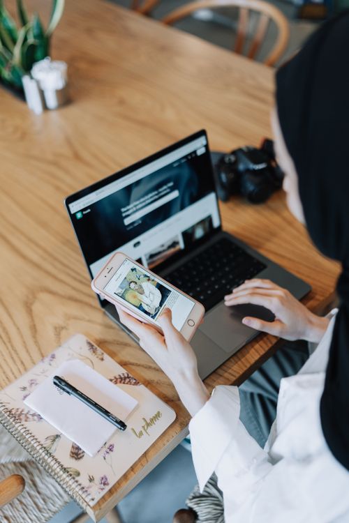 Vrouw die op laptop en telefoon reviews van stukadoors vergelijkt voordat ze een keuze maakt