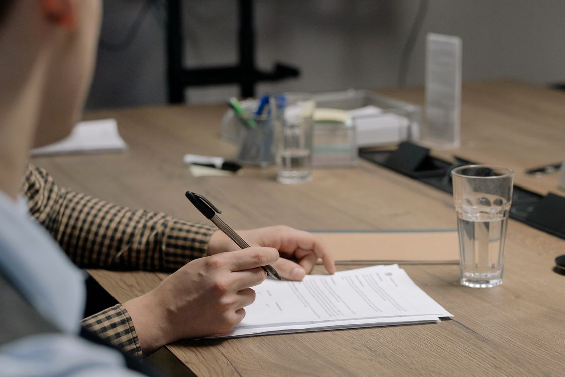 Hand die een garantiedocument ondertekent aan een houten tafel