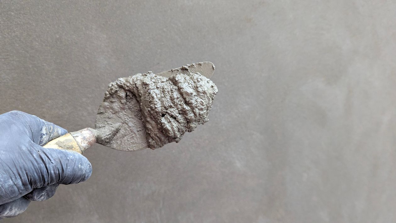 Vakman met handschoen die een pleisterspaan met gips vasthoudt, klaar om aan de slag te gaan bij een klant in Tilburg