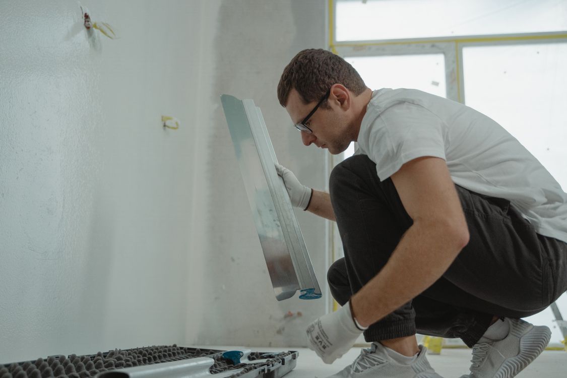 Stukadoor die met een metalen spaan verse pleisterlaag aanbrengt op een binnenmuur tijdens een renovatie