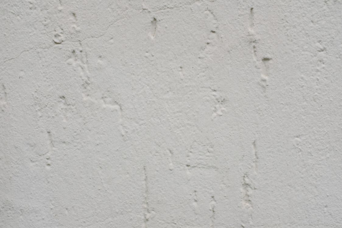 Witte gladde pleisterwand met lichte structuurverschillen die de droging zichtbaar maken