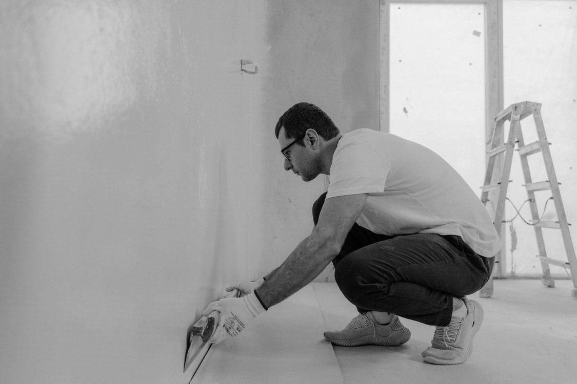 Vakman die met een spaan pleisterwerk aanbrengt op een binnenwand in een woning in Tilburg