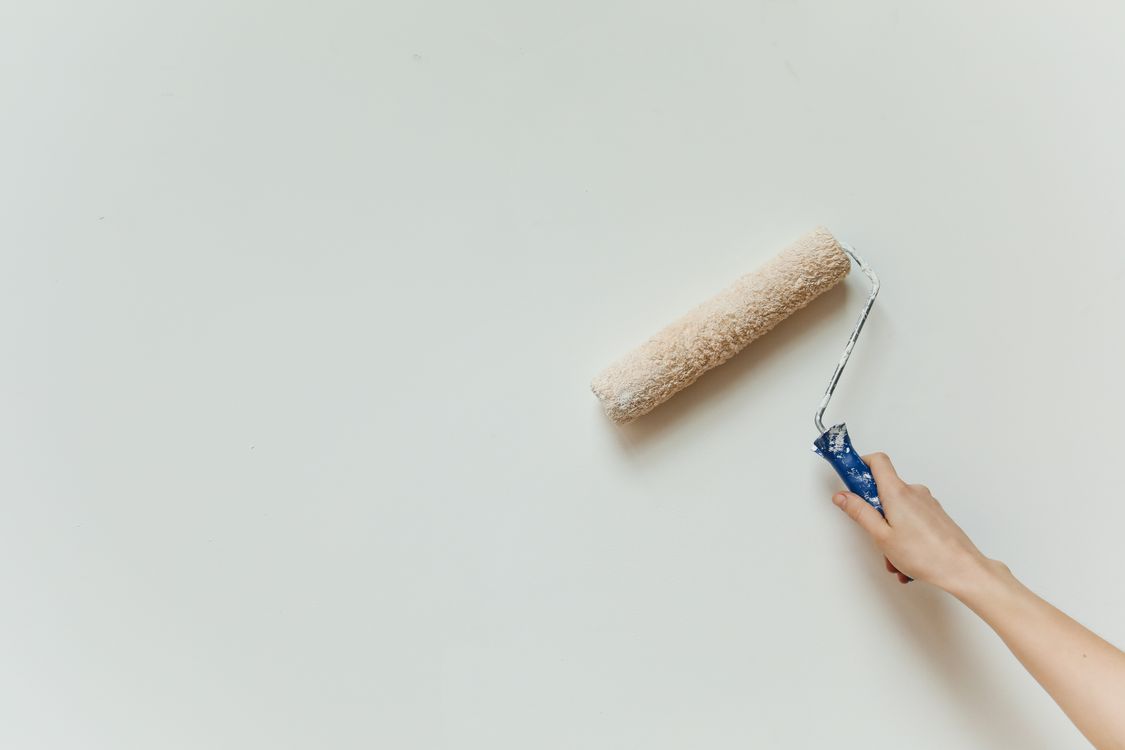 Hand die met een verfroller een binnenmuur schildert tijdens een renovatie