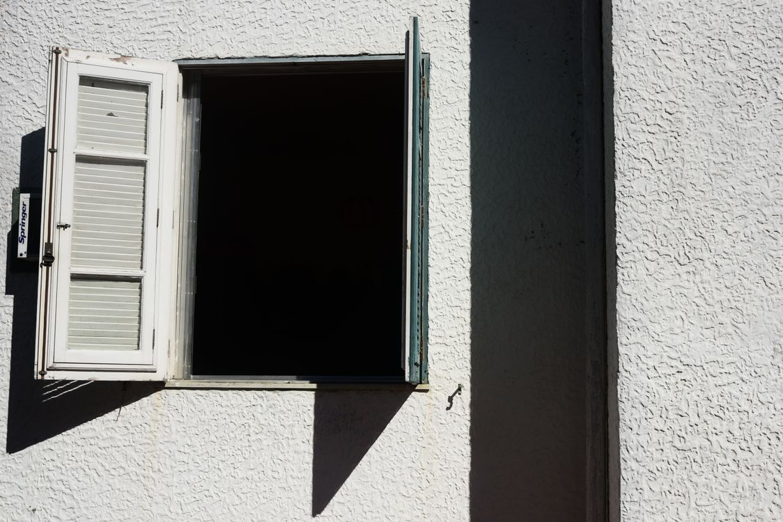 Open raam met zonlicht op een witte muur dat de ruimte ventileert tijdens het drogen
