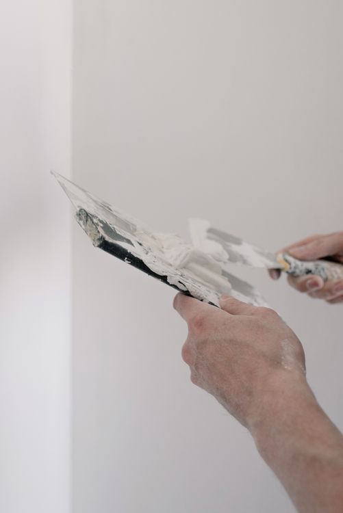 Stukadoor in werkkleding die met troffel handmatig stucwerk uitvoert op een wand