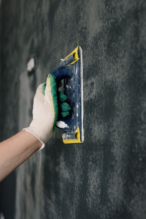 Vakman met spatel die nauwkeurig pleisterwerk aanbrengt op een binnenmuur in Tilburg