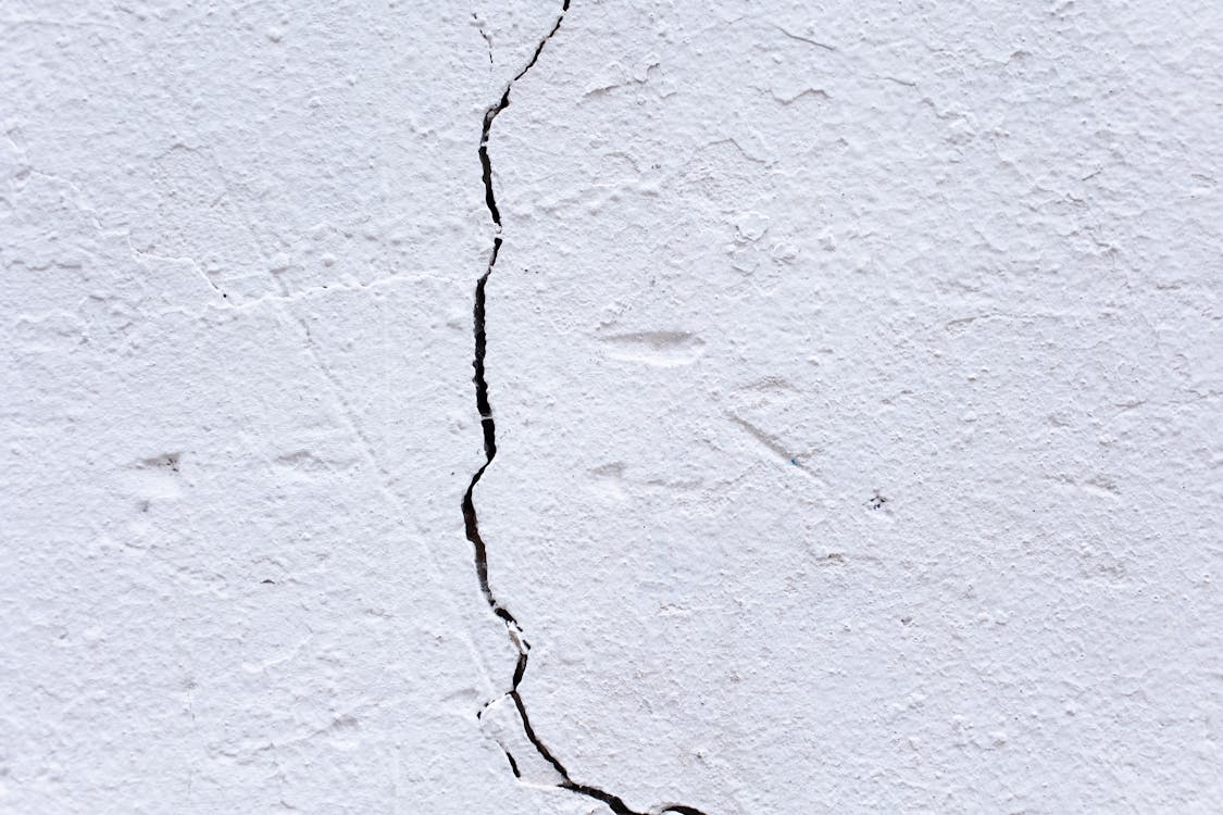 Ruwe pleisterwand met zichtbare scheur die om reparatie vraagt
