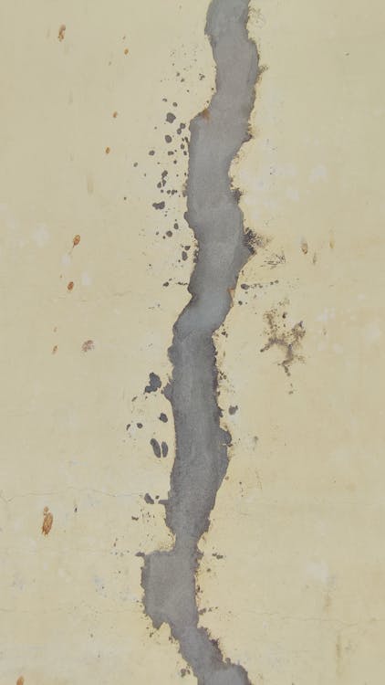 Close-up van een gerepareerde scheur in een cementwand met zichtbaar contrast