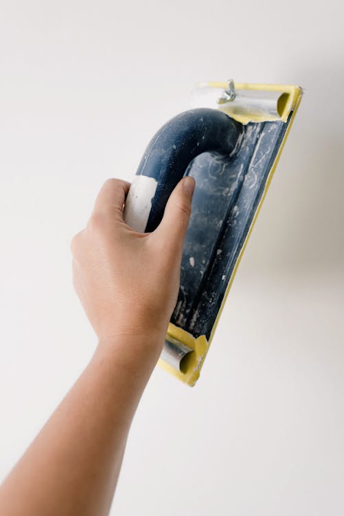 Vakman die met schraper een wand voorbereidt tijdens renovatie