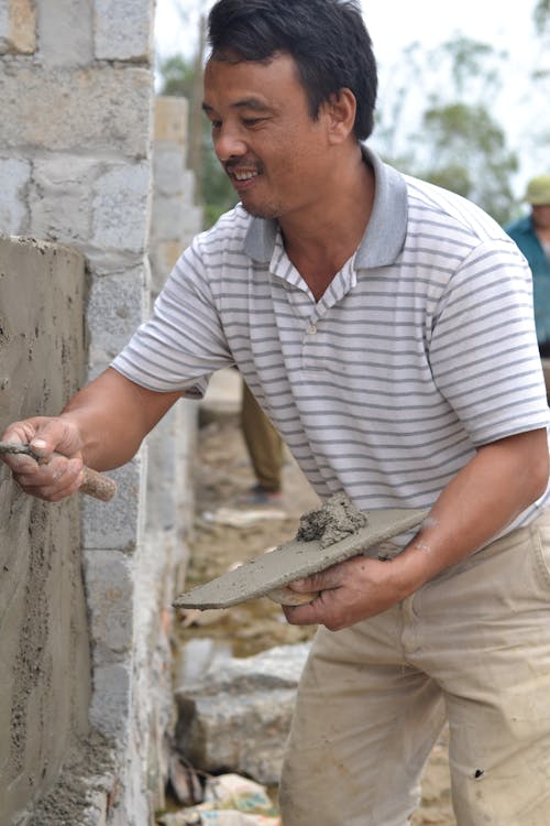 Vakman die cement aanbrengt op een muur tijdens renovatiewerk