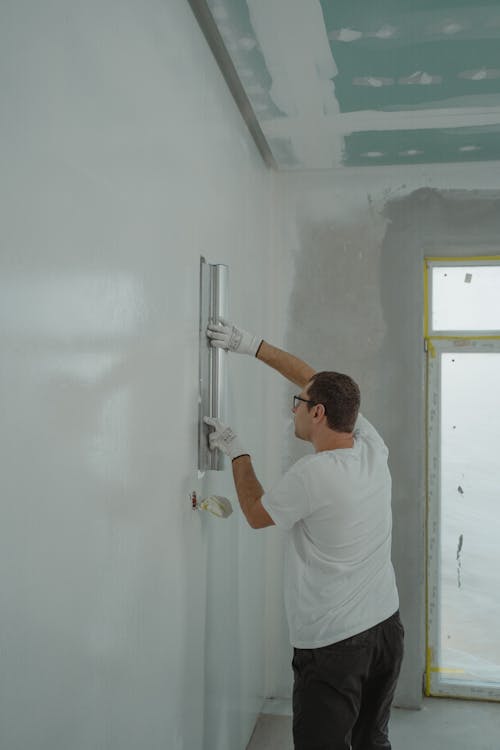 Vakman die een binnenmuur schildert met verfroller tijdens renovatie