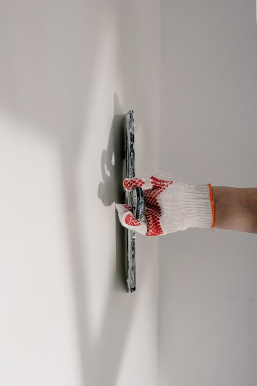Vakman die wand uitvlakt met een rei tijdens stucwerkrenovatie