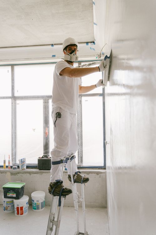Stukadoors in beschermende kleding die dunpleister aanbrengen op een binnenmuur