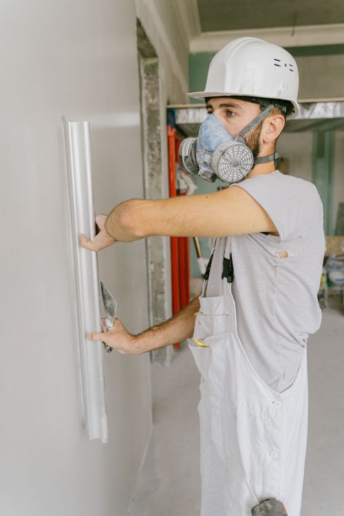 Vakman die met een metalen spaan verse gipsmortel aanbrengt op een binnenwand