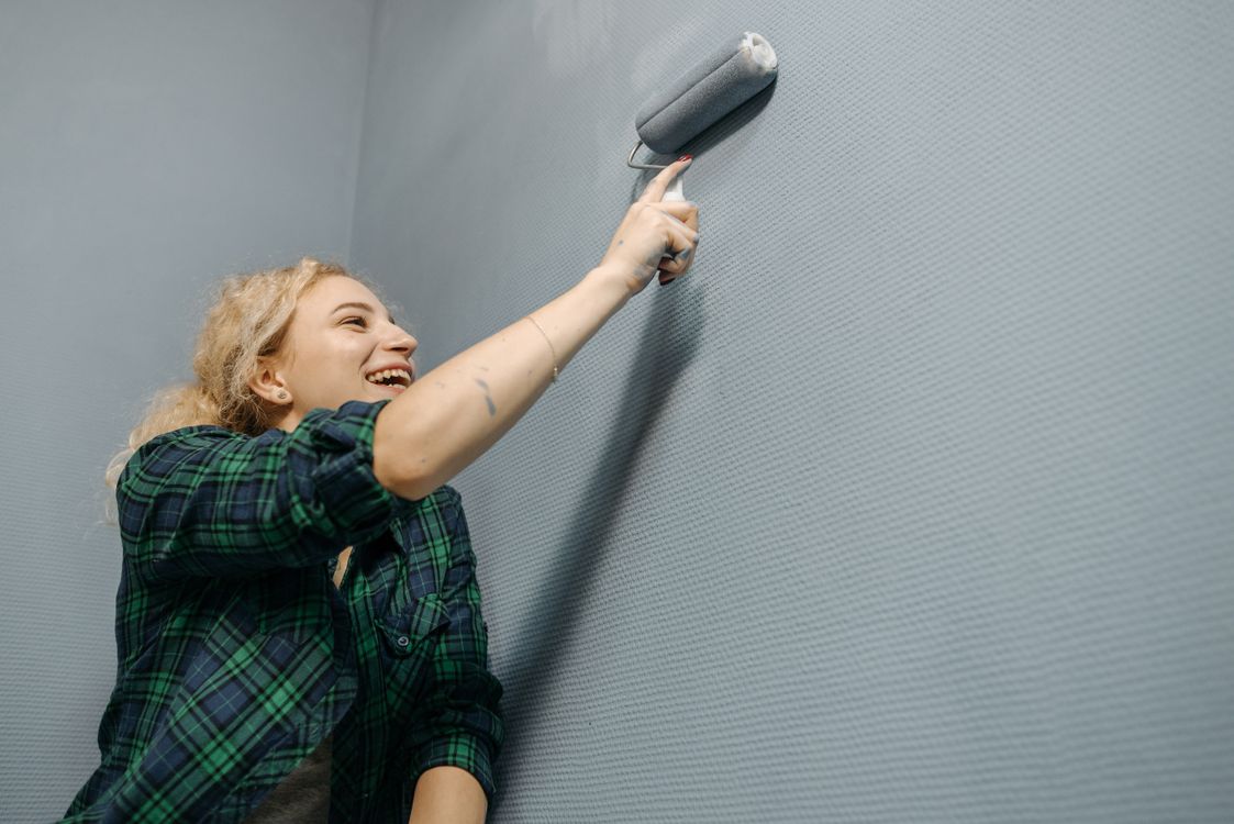 Vrouw die een muur schildert met een verfroller bij een renovatie