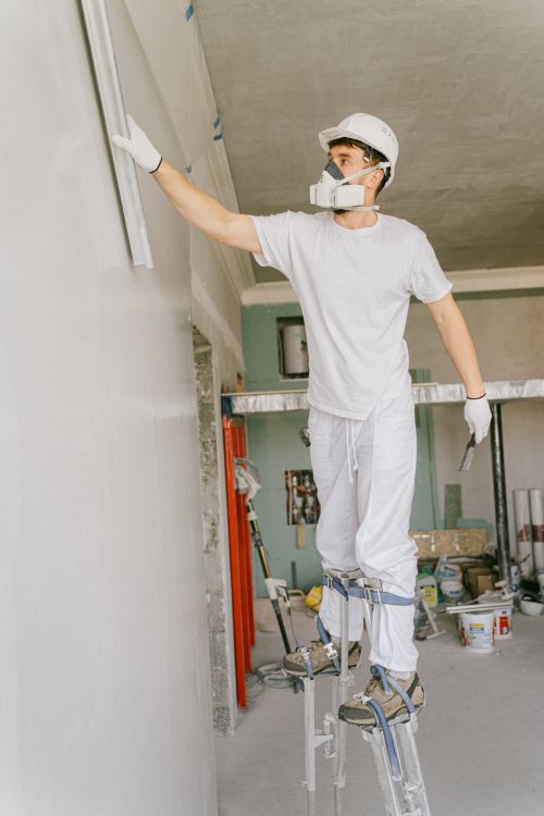 Vakman die een binnenwand behandelt tijdens renovatiewerk
