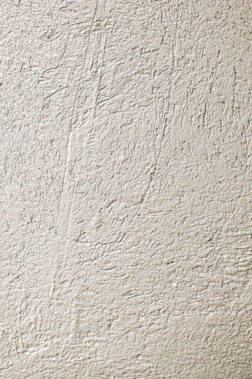 Close-up van een gestucte witte muur als referentie voor het eindresultaat