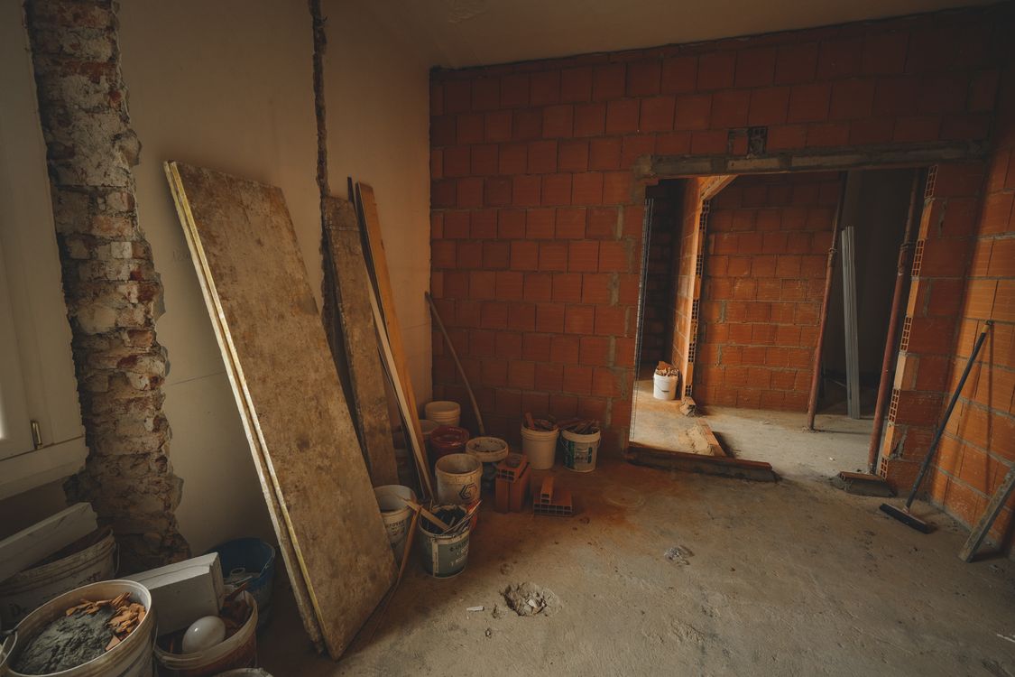 Ruwe bakstenen muur met gereedschap, klaar voor controle van de ondergrond vóór sierpleister