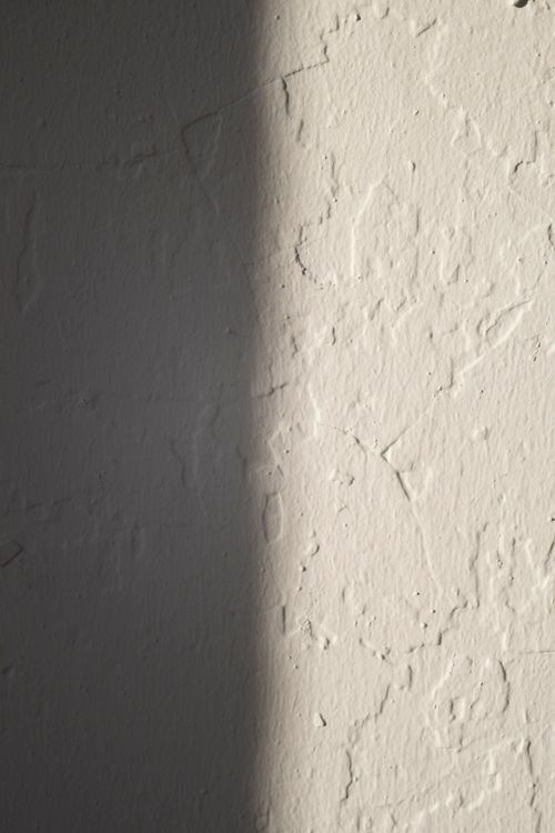 Wit gepleisterde muur met een lichte textuur, het startpunt vóór een sierpleisterlaag