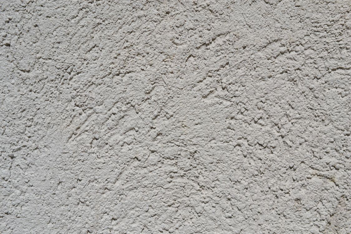 Close-up van een sierpleisterwand met een fijne, tastbare korrelstructuur