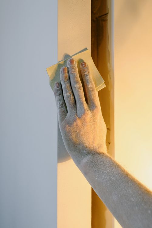 Persoon die met vuile handen zelf een muur probeert glad te strijken