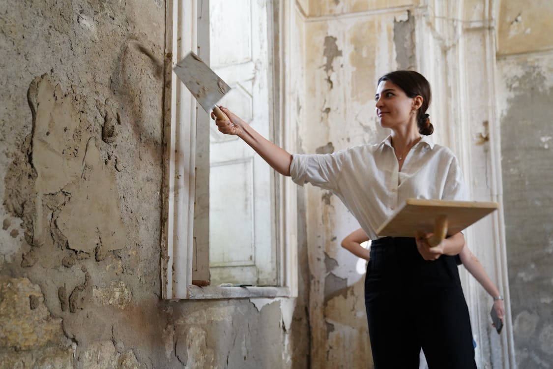 Stukadoor die dunpleister aanbrengt op een binnenmuur van een woning in renovatie