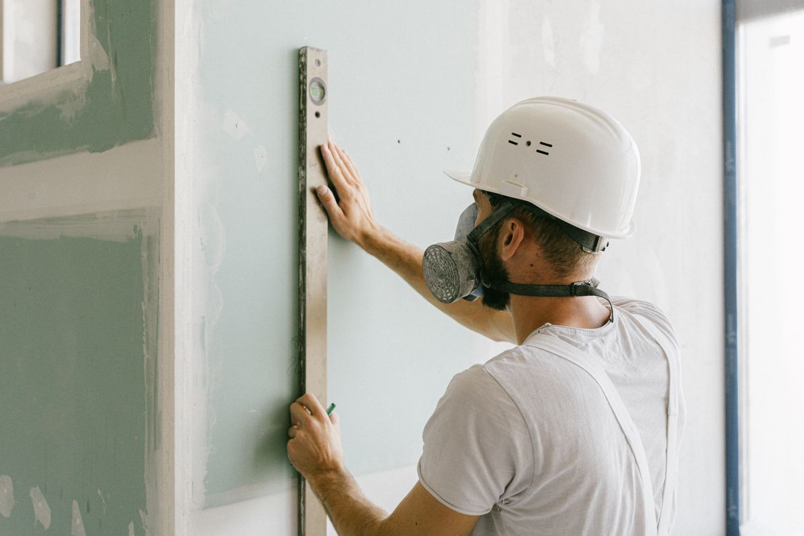 Vakman die met een waterpas de vlakheid van een muur controleert in een woning in Tilburg
