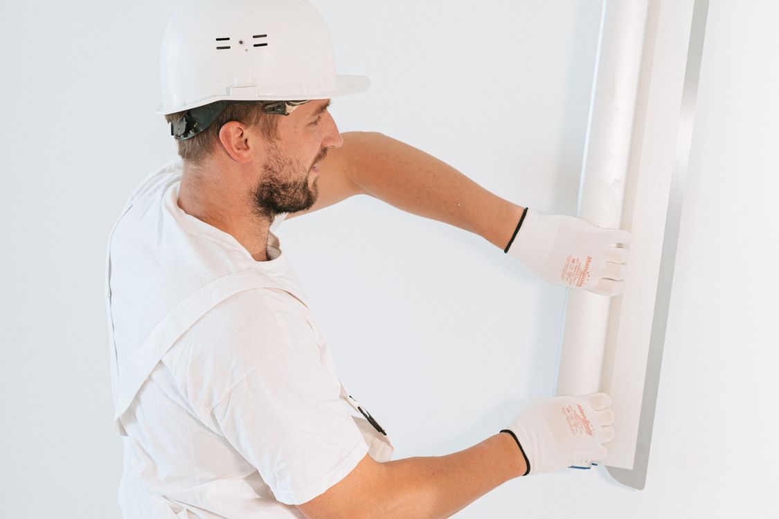 Vakman die met werkhandschoenen en helm een muur voorbereidt voor stucwerk in een woning in Tilburg