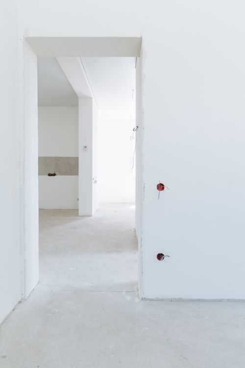 Lichte, kale kamer met witte wanden klaar voor een kleine zelfklus