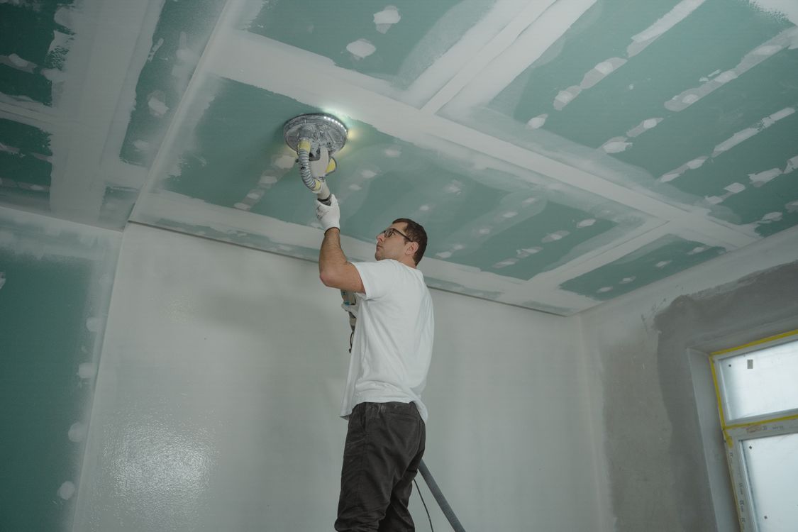 Vakman die het plafond poleert tijdens een binnenrenovatie in een woning