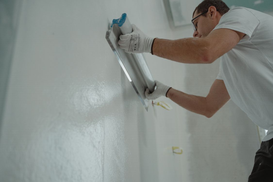 Man brengt pleistermortel aan op een binnenwand bij een renovatieklus